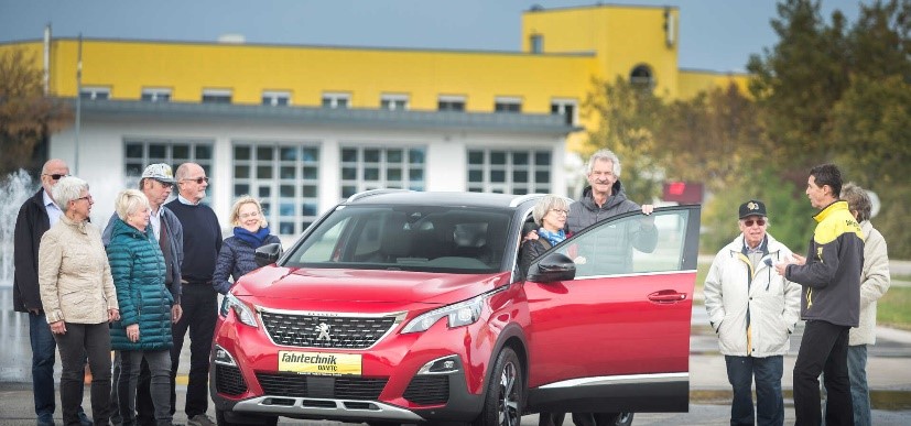 Personengruppe um rotes Auto