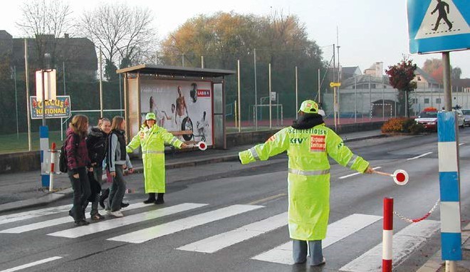 Schülerlotsen ermöglichen einer Schülergruppe das Überqueren der Straße